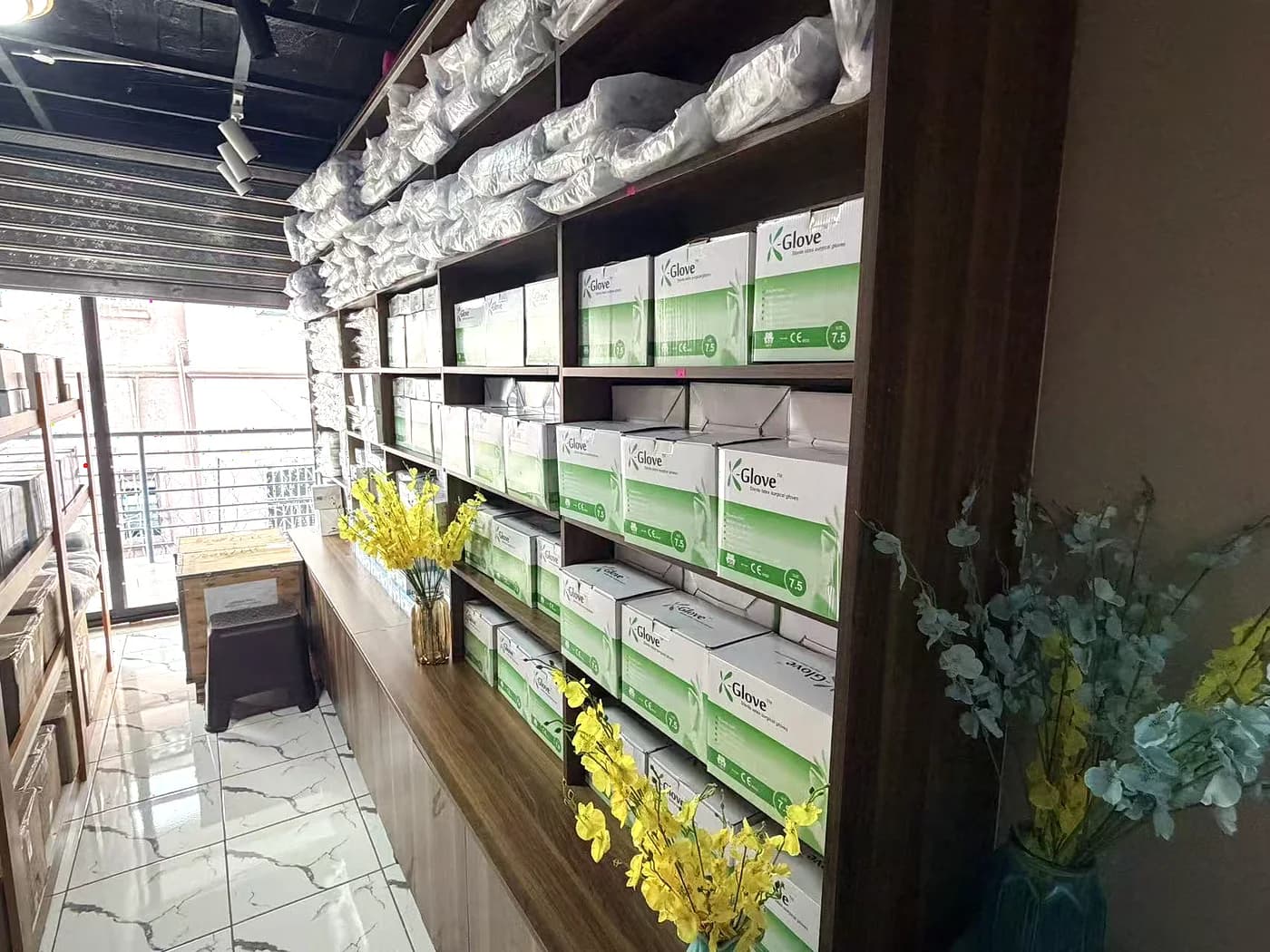 Boxed gloves and consumables stacked on shelves beside the window